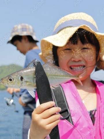 女の子が釣った魚をフィッシュグリップでつかんでいる写真