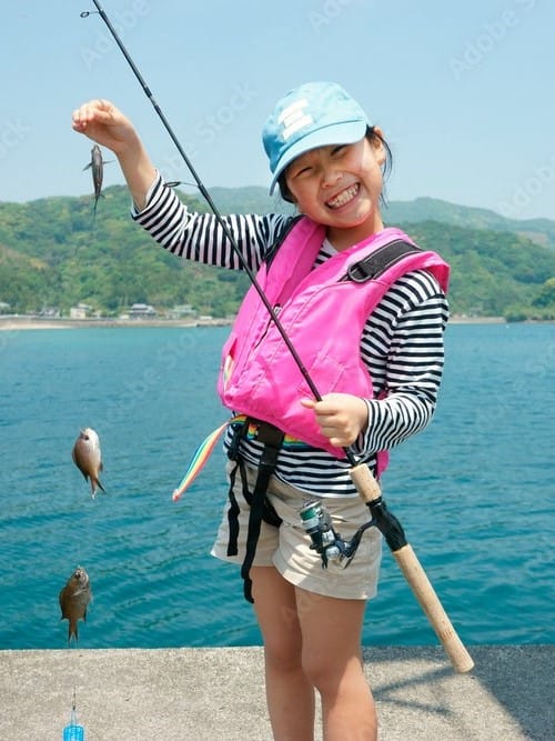 笑顔の女の子が魚を釣って喜んでいる写真