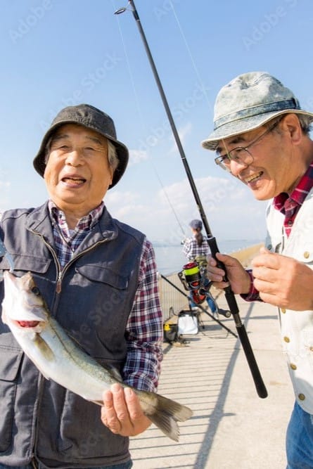 年配の男性2人が大きい魚を釣り上げて喜んでいる写真