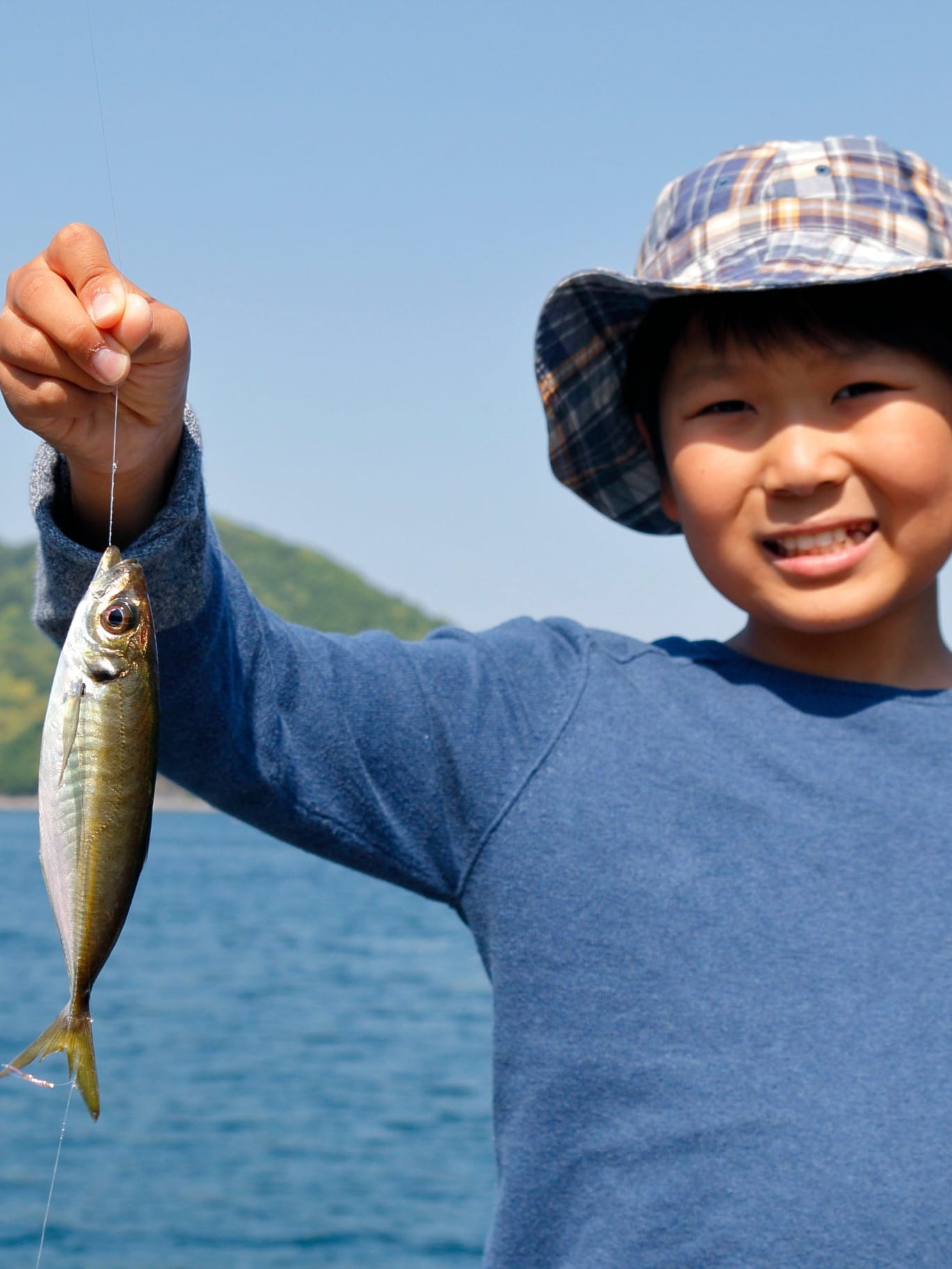 男の子が魚を釣って喜んでいる写真